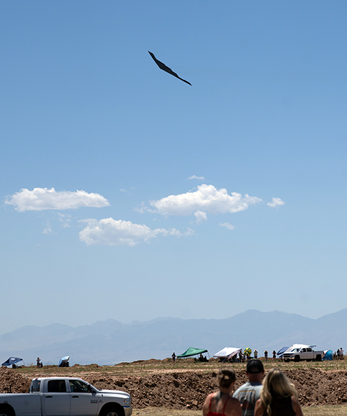 A B2 Bomber flies over employees watching the air show