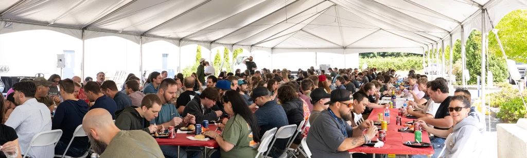 Employees eating BBQ under tent