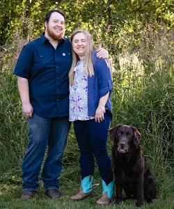 Kayla, her husband and dog pose for a photo