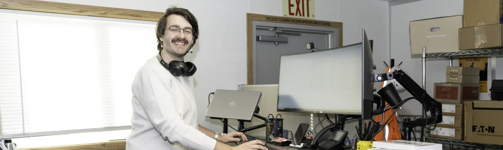 Ben stands at computer desk